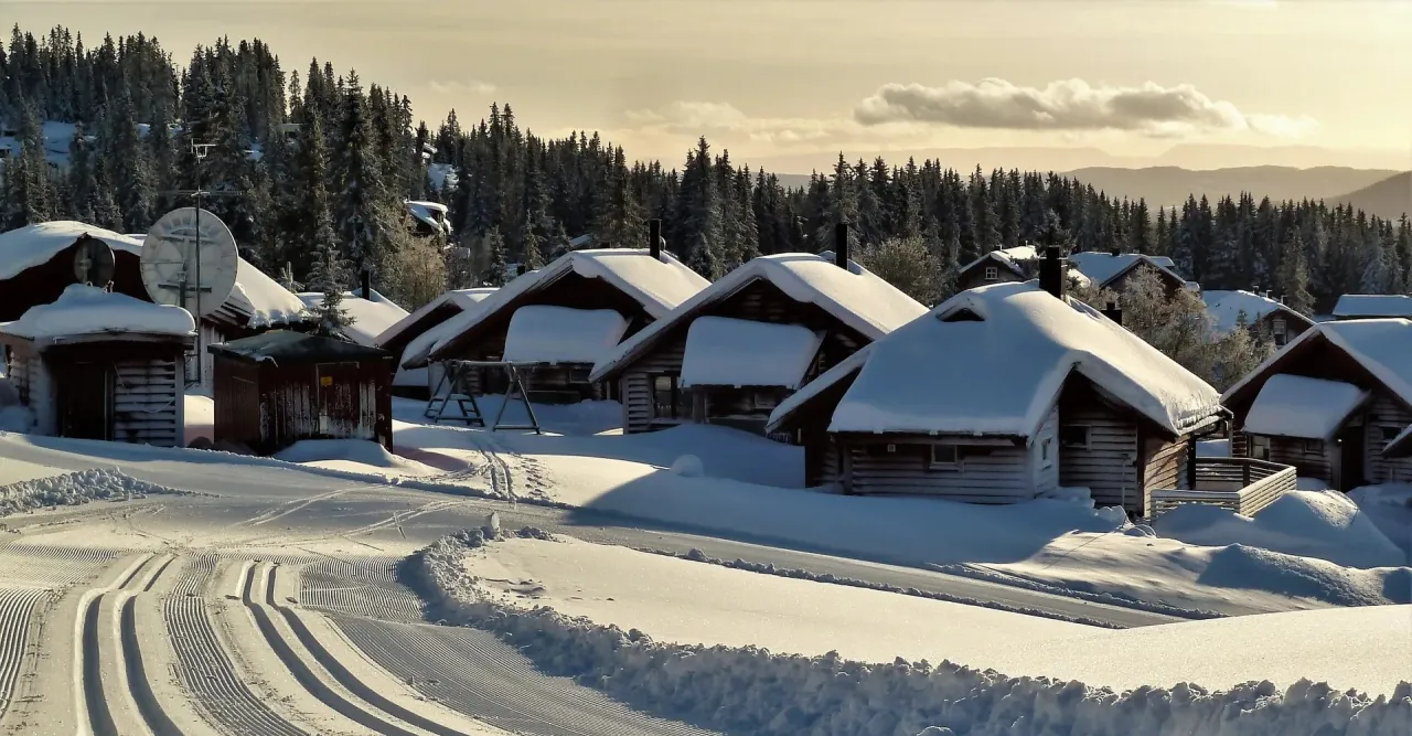 Røde hytter med snø på taket og skiløype i forgrunn